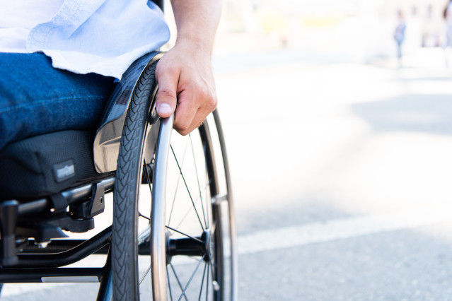 ein Mann sitzt im Rollstuhl und seine Hand fasst das Rollstuhlrad (verweist auf: Datenschutz bei der Verordnung von Heil- und Hilfsmitteln)
