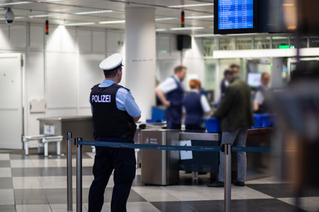 ein Bundespolizist steht an einer Gepäckkontrolle am  Flughafen (verweist auf: Bundespolizei)